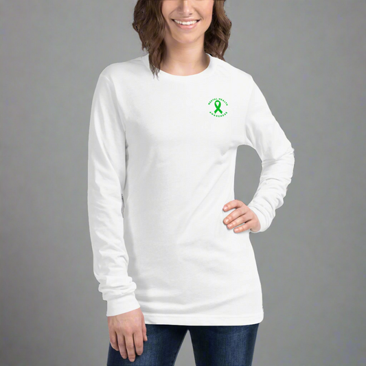 A woman smiles against a plain gray background, wearing the You Are Not Alone Mental Health Awareness unisex long sleeve tee featuring a small green ribbon and 988 crisis hotline text on the upper left chest.