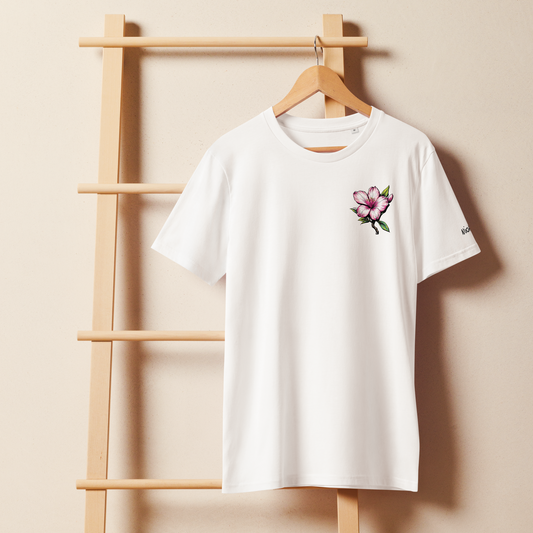 White t-shirt with a floral design on a wooden hanger against a beige wall.