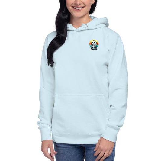 A woman in a light blue Stay Positive Unisex Hoodie, adorned with a lively skull graphic, radiates joy through her bright smile and confident stance. Her long dark hair complements the hoodie which she pairs with blue jeans, embodying self-care and mental well-being.