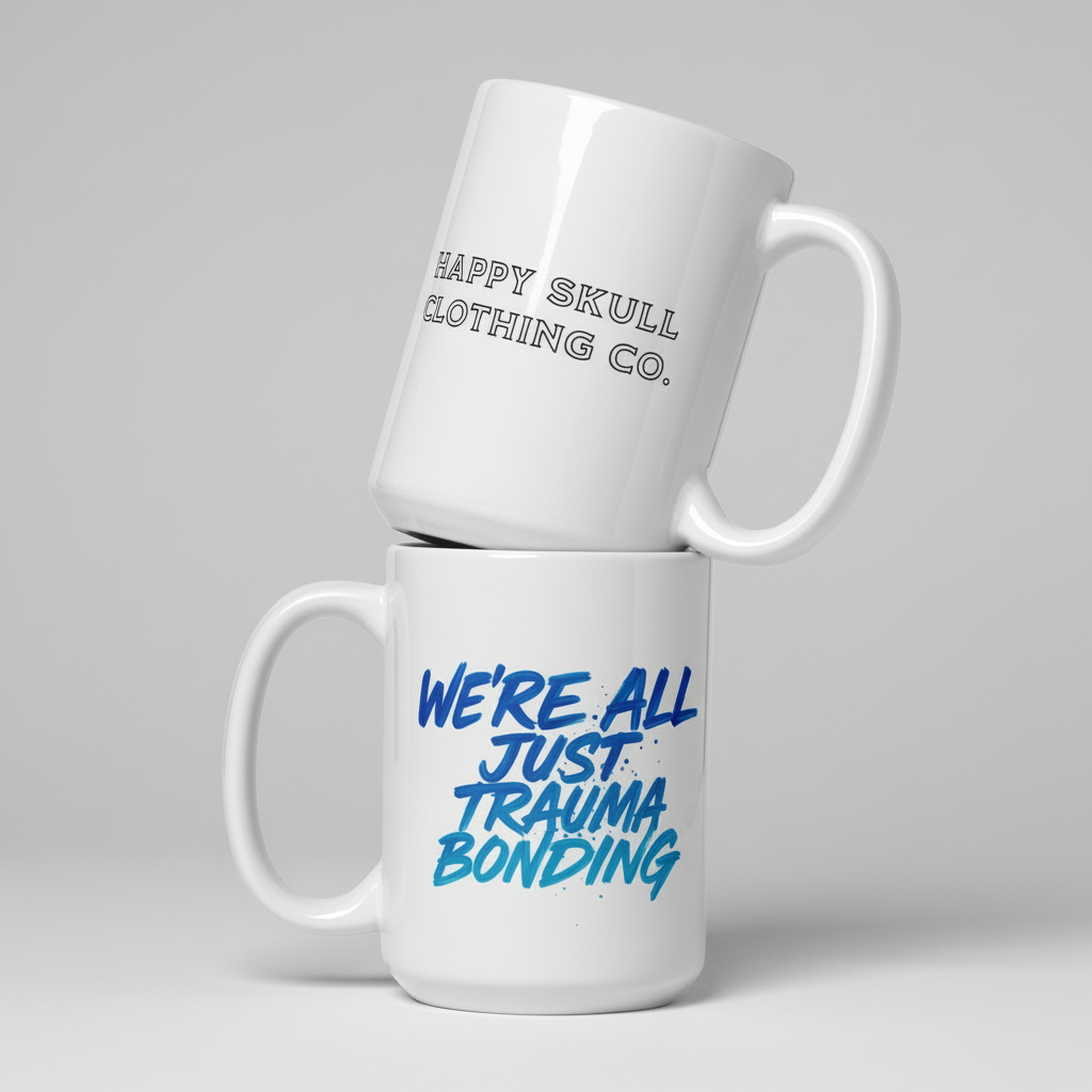 The We’re All Just Trauma Bonding 15oz Mug (New) showcases "HAPPY SKULL CLOTHING CO." on top and "WE’RE ALL JUST TRAUMA BONDING" boldly below—a modern ceramic mug for your collection.