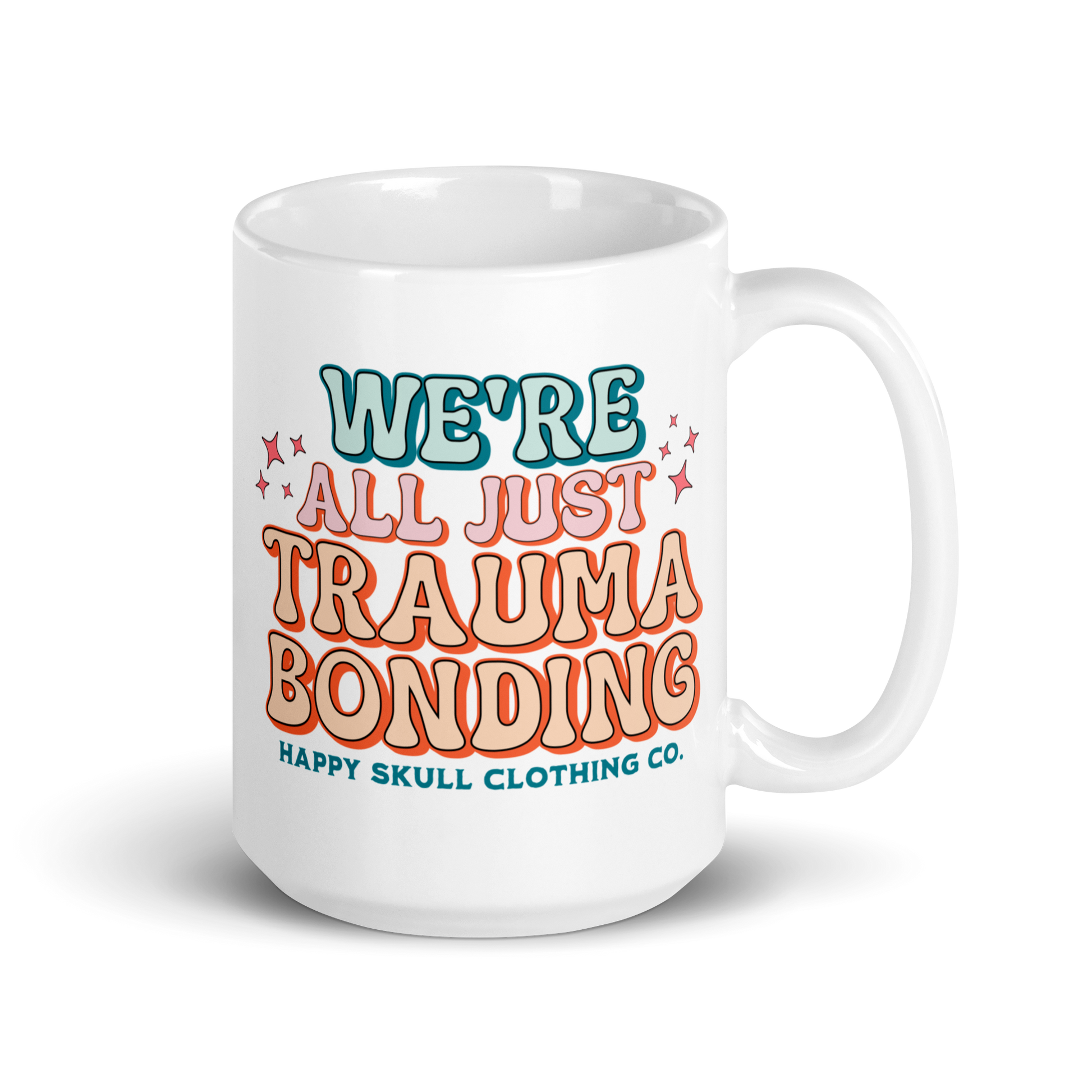 The We’re All Just Trauma Bonding - 15oz Coffee Mug features colorful text with decorative stars and “Happy Skull Clothing Co.” in teal and orange—an ideal mug for your healing journey.